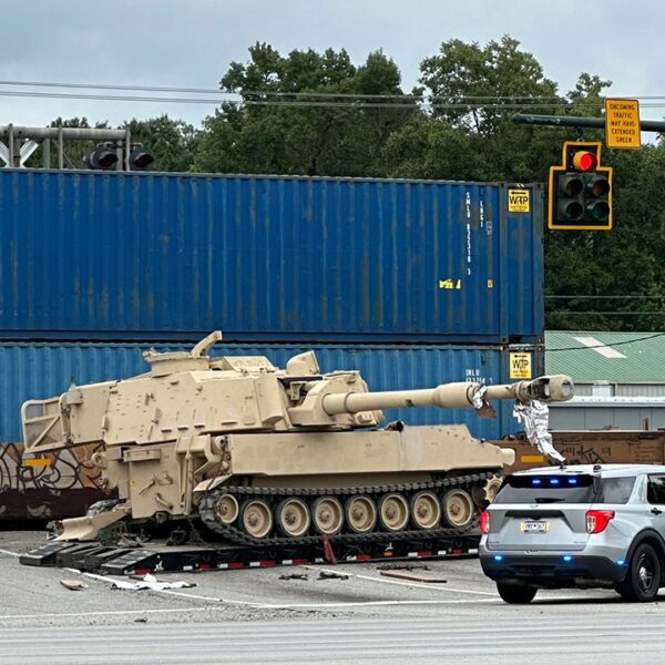 Train collides with army cell artillery automobile being hauled on a semi-truck